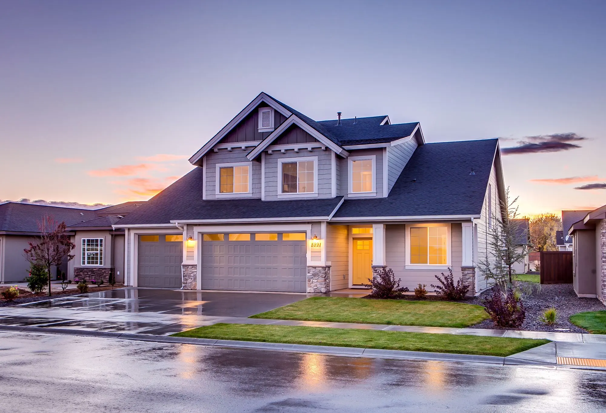 Two-story suburban home with lights on at dusk